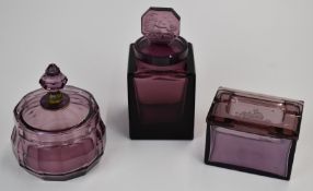 Three pieces of amethyst glass comprising a Heinrich Hoffman lidded box and scent bottle both with