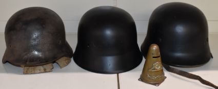 Two replica German civic steel helmets together with a replica military example stamped Q62 and a