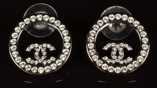 A pair of Chanel earrings with iconic CC logo in a circular surround set with crystal, marked Chanel