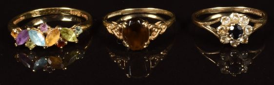 Three gold rings, one set with quartz, one with a sapphire and cubic zirconia and the other peridot,