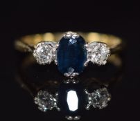 An 18ct gold ring set with an oval cut sapphire of approximately 1ct and two diamonds, 2.8g, size L