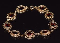 A 9ct gold bracelet made up of oval pierced links set with oval cut garnets, 7.8g