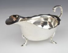 Edward VII hallmarked silver sauce boat with scroll handle, raised on three feet, Chester 1908,