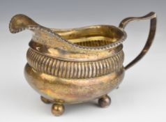 Georgian hallmarked silver milk jug with part reeded body, raised on four ball feet, London 1812,