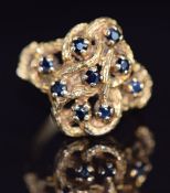 A 9ct gold ring set with sapphires in a textured knot setting, 5.2g, size N