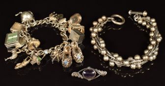 A silver charm bracelet with fifteen silver charms including Nuvo hovercraft, two banknotes,