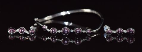 A suite of 18k white gold jewellery comprising bangle and earrings set with diamonds and purple gold