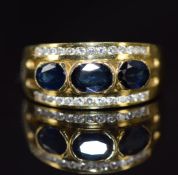 An 18k gold ring set with three sapphires and two rows of diamonds, 7.7g, size L