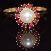 An 18ct gold ring set with a pearl surrounded by rubies, 3.4g, size S