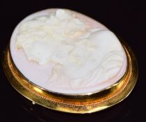 A yellow metal brooch set with a coral cameo depicting a young woman, 24.8g