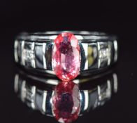 An 18ct white gold ring set with a Ceylon padparadscha sapphire and diamonds, 7.1g, size N