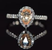 A platinum ring set with an orange pear cut sapphire of approximately 1.25ct surrounded by diamonds,