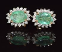 A pair of 9ct gold earrings each set with an oval cut emerald of approximately 0.6ct surrounded by
