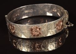 A hallmarked silver bangle with gold floral decoration