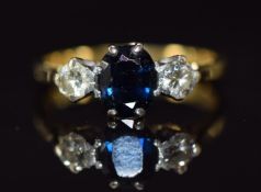 An 18ct gold ring set with an oval cut sapphire of approximately 1.1ct and two diamonds each