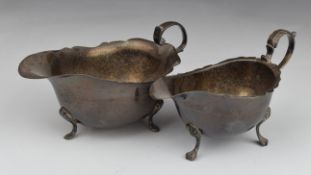 Two early 20thC hallmarked silver sauce boats, both with shaped edges and raised on three feet,