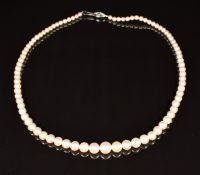 A single strand of cultured pearls with an 18ct white gold clasp set with an emerald and diamonds