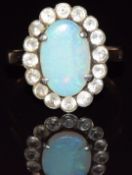 A 9ct gold ring set with an opal surrounded by white sapphires, 2.9g, size P