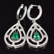A pair of 18k white gold earrings each set with a pear cut emerald of approximately 0.5ct surrounded