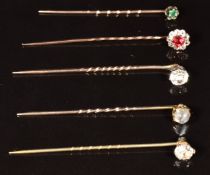 Four 9ct gold stick pins, one set with an emerald, one moonstone, one spinel and one paste