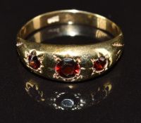 A 9ct gold ring set with three garnets in star settings, 2.5g, size Q