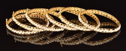 Six 22ct gold bangles set with natural pearls, in original box 'Mudaifa Jewellery Bahrain', 64.2g
