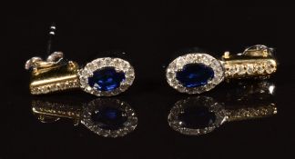 A pair of 14k gold bi-coloured reversible earrings each set with an oval cut emerald, oval cut