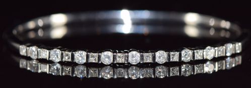 An 18ct white gold bangle set with nine round brilliant cut diamonds and ten princess cut
