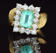 An 18ct gold ring set with an emerald cut emerald of approximately 1.8ct surrounded by diamonds,