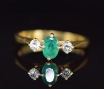 An 18ct gold ring set with an oval cut emerald of approximately 0.5ct and two diamonds, 3g, size L