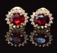 A pair of 18ct gold earrings each set with an oval cut ruby of approximately 0.7ct surrounded by