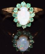 A 9ct gold ring set with an opal surrounded by emeralds, 1.6g, size L