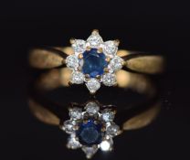 A 9ct gold ring set with a round cut sapphire surrounded by diamonds, 2.9g, size O