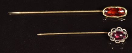 A 14k gold stick pin set with a garnet cabochon (1.9g) and another stick pin set with a garnet