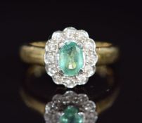 A 9k gold ring set with an oval cut emerald of approximately 0.7ct surrounded by diamonds, 5.5g,