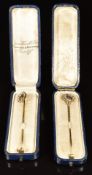 Two Edwardian 15ct gold stick pins, one in the form of a horseshoe and the other a circle set with
