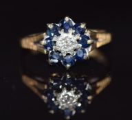 A 9ct gold ring set with a diamond surrounded by sapphires, 2.3g, size M