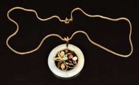 A 14k gold pendant set with a jade disc with a gold foliate design to the centre set with jade