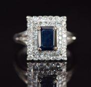 An 18k white gold ring set with a sapphire and diamonds in a tiered setting, 7.6g, size O