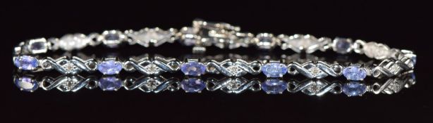 A 14k white gold bracelet set with eleven oval cut tanzanites and eleven round cut diamonds, with