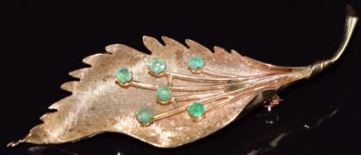 A 14k gold brooch in the form of a leaf set with emeralds, 8g