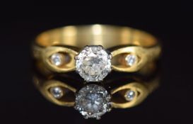 An 18ct gold ring set with a round cut diamond of approximately 0.5ct and two smaller diamonds to