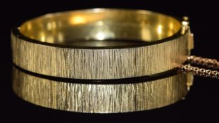 A rolled gold bangle with ridged decoration, marked KJ Amerio