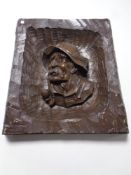 A carved wooden plaque depicting a man smoking a pipe