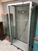 An illuminated glass display cabinet on casters,