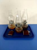 A tray containing three glass oil lamps together with two hip flasks