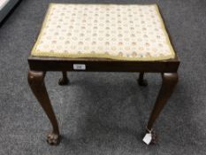 An upholstered beech dressing table stool on carved lion paw feet