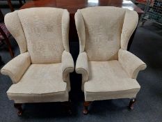 A pair of wingback armchairs in cream upholstery
