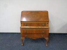 A walnut Queen Anne style bureau on claw and ball feet