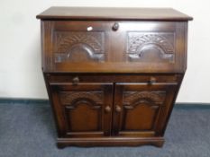 An oak writing bureau fitted double door cupboard and drawer beneath